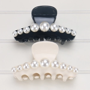 Detailed close-up of acetate shark hair clips with gradient faux pearls in black and white