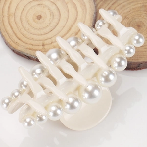 Detailed view of cream-colored acetate shark hair claw clip with elegant pearl embellishments