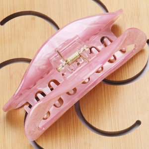 Macro shot of large pink acrylic hair claw clip with gold glitter and marble texture