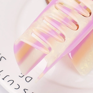 Macro shot of 14cm gradient resin hair claw with glitter finish on a white ceramic plate