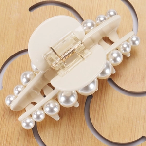 Detail of cream acetate claw clip with double rows of white pearls and golden spring