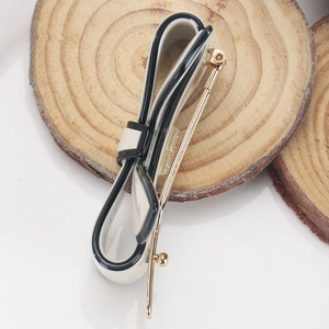 Detail view of acetate bow hair clip in cream and black on a rustic wooden base