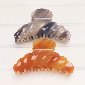 Macro shot of large acetate shark hair claw clips in tortoise shell and amber orange