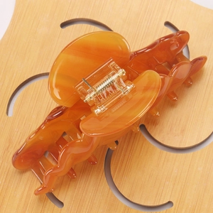 Close-up of a glossy amber acetate shark hair claw clip showing its smooth texture