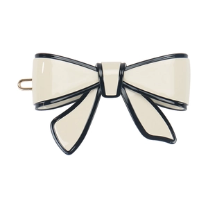 Close-up of cream and black acetate bow hair clip with polished finish and gold metal base