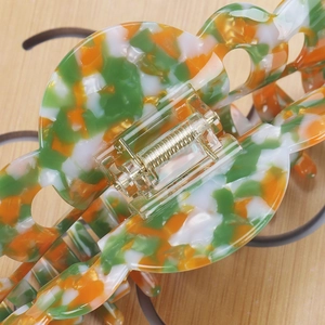 Macro shot of large acetate hair claw clip showing colorful marble texture and golden spring