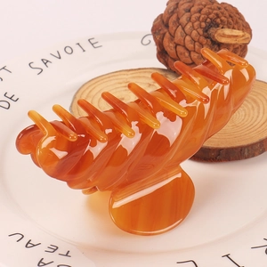 Close-up of amber acetate hair claw clip with marble texture on elegant white plate