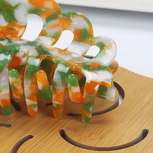 Detailed close-up of 14cm acetate hair claw clip with orange and green marble patterns