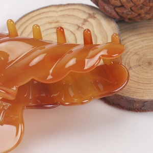 Macro view of dark amber acetate hair claw clip with glossy finish and wavy edges