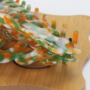Macro shot of large acetate hair claw clip with green and orange marble pattern finish