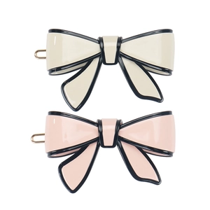 Elegant bow hair clips in beige and pink with black trim on a clean white background