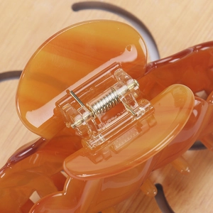Macro shot of durable metal spring on large amber acetate claw clip for women