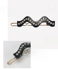 Détail d'une pince à cheveux ondulée en acétate noir et strass, 5,9 par 1,5 cm