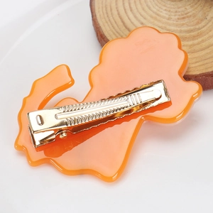Détail macro d'une pince à cheveux lion en acétate orange avec base dorée