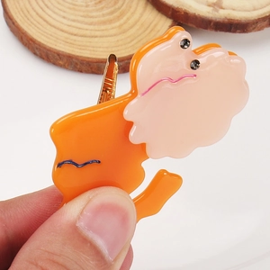 Gros plan d'une pince oiseau en acétate orange et rose avec yeux en strass et clip doré