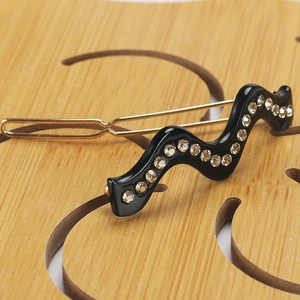 Vue rapprochée d'une barrette à cheveux noire ondulée avec des strass champagne
