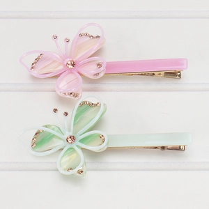 Détail de deux barrettes papillon en acétate avec base en métal doré et petits strass