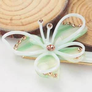 Détail macro d'une élégante pince à cheveux papillon vert clair avec strass et clip doré