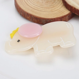 Détail d'une pince à cheveux éléphant en acétate beige avec un petit strass brillant