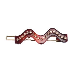 Détail de la barrette à cheveux ondulée en acétate avec strass et base en métal doré