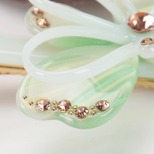 Détail de la pince à cheveux élégante en acétate avec motif papillon vert et cristaux