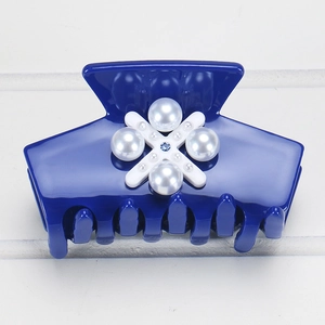 Détail d'une pince à cheveux bleu roi en acétate avec croix blanche et perles