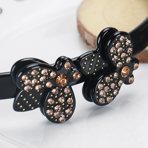 Detailed close-up of amber rhinestones and gold beads on a black acetic headband