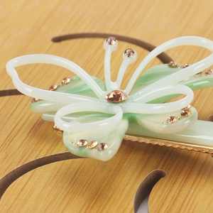 Vue macro de la pince à cheveux papillon en résine verte avec détails en cristal ambre