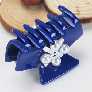 Détail d'une pince à cheveux en acétate bleu foncé avec fleur de perles et strass