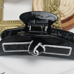 Détail d'une grande pince à cheveux noire avec un nœud élégant orné de strass brillants