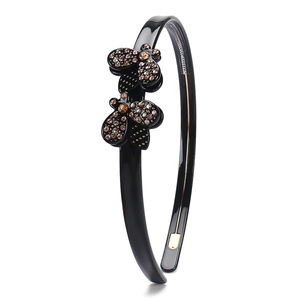 Detail of black acetate headband with brown rhinestone flowers and non-slip inner teeth