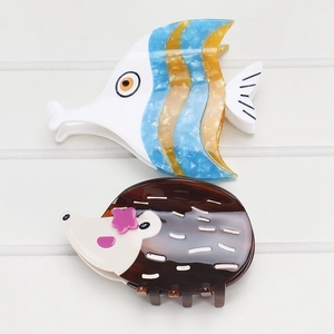 Détail de pinces à cheveux en acétate motifs poisson et hérisson aux textures fines