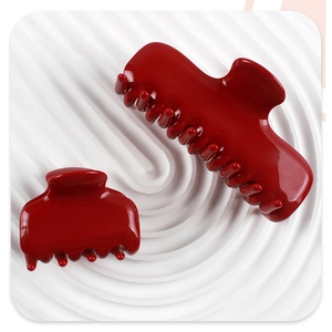 Detalle de pinzas para el cabello rojas brillantes de varios tamaños sobre base blanca