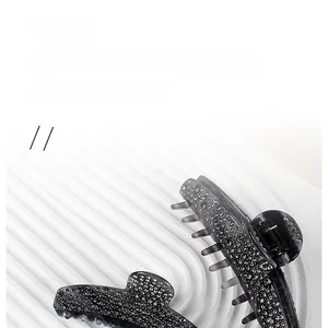 Detail of grey acetate hair claw clips with rhinestones on a white display tray