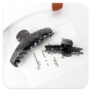 Close-up of two grey acetate hair claws with sparkling rhinestones on white background