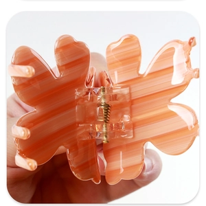 Makro-Detail der Haarklammer Schmetterling mit orangefarbener Streifen-Textur und Goldfeder