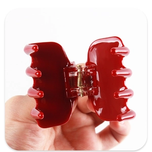 Detalle de una pinza para el pelo rojo vino brillante con muelle de metal dorado