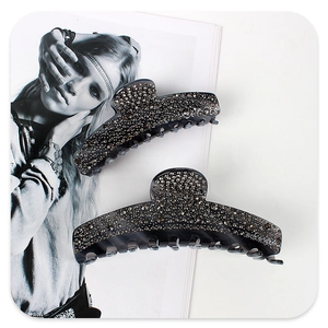 Detail view of two smoky grey acetate hair claws with sparkling rhinestones on a magazine