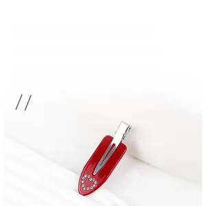 Détail de la pince à cheveux en acétate rouge brillant avec motif de cœur en strass