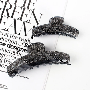 Elegant smoke gray acetate hair claw clip set with sparkling rhinestones on magazine background