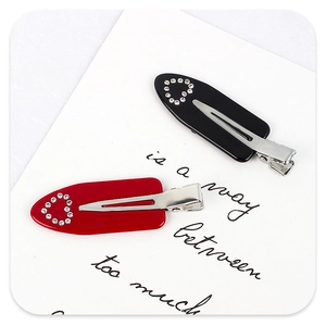 Détail de barrettes en acétate rouge et noir avec motifs de cœurs en strass brillants