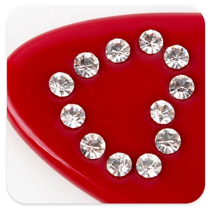 Vue macro de 11 strass clairs sertis en cœur sur une pince à cheveux rouge polie
