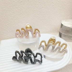 Detail showing large wavy acetate hair claws with marble texture in pink, white, and grey