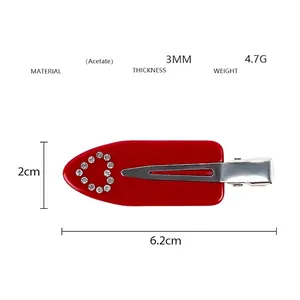 Vue détaillée de la pince à cheveux en acétate rouge de 6,2cm avec cœur en strass