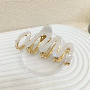 Detail shot of wavy pearlized acetate hair claw clip with golden metal base and teeth