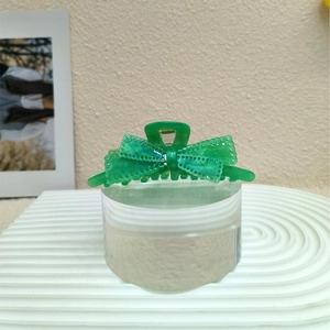 Dettaglio della pinza per capelli in acrilico verde traslucido con fiocco e glitter