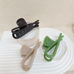 Detailed view of large PVC shark hair clips in black, beige, and matcha green colors