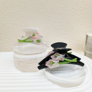 Detail view of large acetate calla lily hair claws in black and cream with floral accents