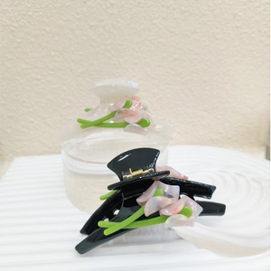 Detail of elegant black and ivory acetate hair claws with white Calla Lily floral design