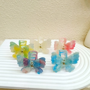 Lot de cinq pinces à cheveux papillon en acrylique dégradé sur un socle blanc élégant
